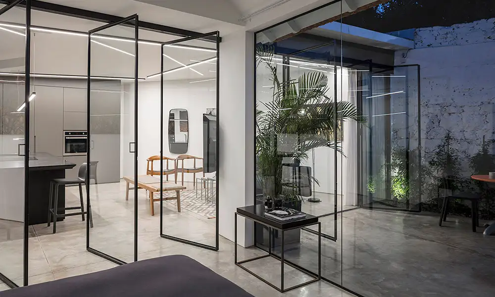 Puertas pivotantes de vidrio con perfilería de aluminio negro en un espacio de coworking de estilo industrial