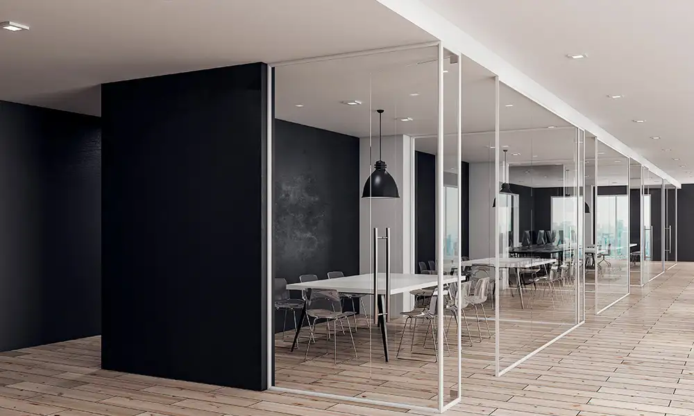 Detalle de mamparas de vidrio con perfiles de aluminio negro en una oficina de diseño.